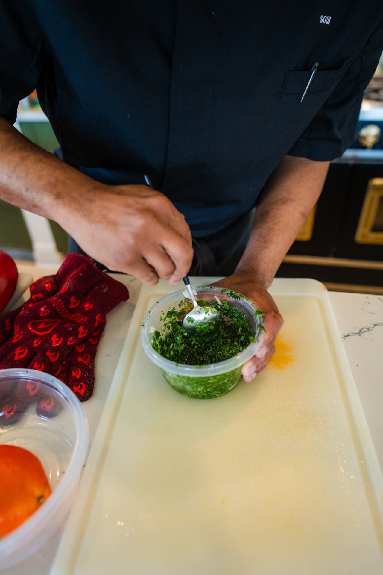 Hands mixing fresh chimichurri in a bowl